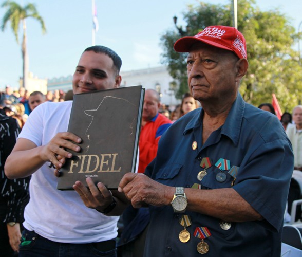 Alcibiades Aguiar Rondón (D), un caravanista de aquel enero de 1959, recibe un álbum de fotos de Fidel de manos de Abran Sánchez González, primer secretario de la organización juvenil en el territorio. Foto: Oscar Alfonso Sosa.