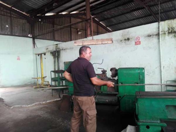 El jefe del taller  muestra una barra de cabilla gruesa recuperada que se destinará a la elaboración de piezas. Foto: Eduardo Sicilia Hernández.